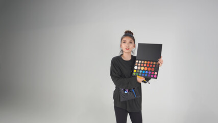 アイシャドウパレットを持ったヘアメイクアーティスト