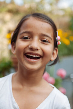 A young south asian girl laughing and looking at camera.