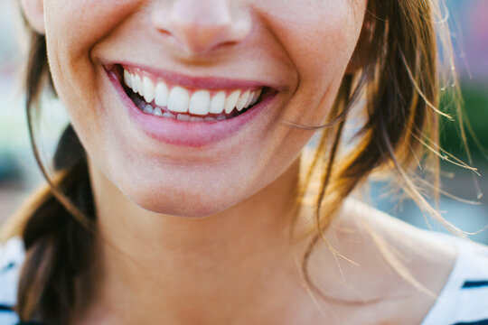 Closeup portrait of a young woman smiling outside.