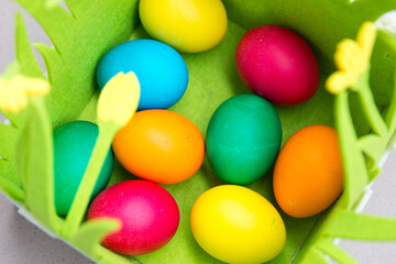 Decorated colorful Happy Eastern chicken eggs outside shot on sunny day with green basket background. Blue, green, orange,red, yellow Paschal eggs, by tradition usually used as gifts during Easter