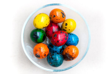 Decorated colorful Happy Eastern quail eggs outside shot on sunny day with green basket background. Blue, green, orange,red, yellow Paschal eggs, by tradition usually used as gifts during Easter tide 
