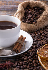 Coffee background with fresh aromatic beans and cup of coffee on a wooden table.