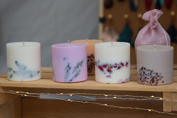 Original handmade candles of unique design, filled with different types of herbs and flowers, decorated by coffee beans and dry leafs and blooms. Organic wax candles for Christmas dinner and New Year 
