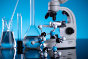 Coronavirus pandemic theme. Science research concerning fast covid tests and anti-covid vaccine. Beakers, microscope and test tubes on blue background.