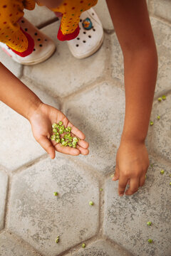 A young girl picking flowers from the floor.