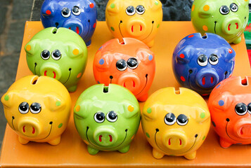 Obraz premium Colorful money boxes, piggy banks on sale on the street market in Europe city of Riga, Latvia. Funny colorful piggy banks for money savings for big dreams, vacation, children future 