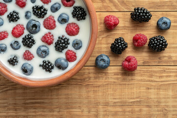 Yogurt with blueberries, raspberries, blackberries, flax seeds in a clay bowl. Served vegetarian dish. Healthy breakfast, healthy food. Background for the menu of restaurants, cafes.