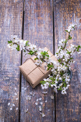 Congratulation set with blooming cherry twig and gift box on a wooden background, copy space.