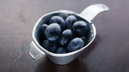 fresh ripe plums lie in an old aluminum colander
