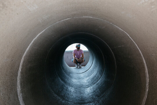 Man crouching in the other end of a long tube