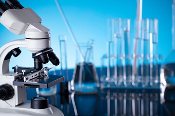 Coronavirus pandemic theme. Science research concerning fast covid tests and anti-covid vaccine. Beakers, microscope and test tubes on blue background.