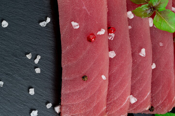 Fresh raw tuna steak with basil. On black rustic background