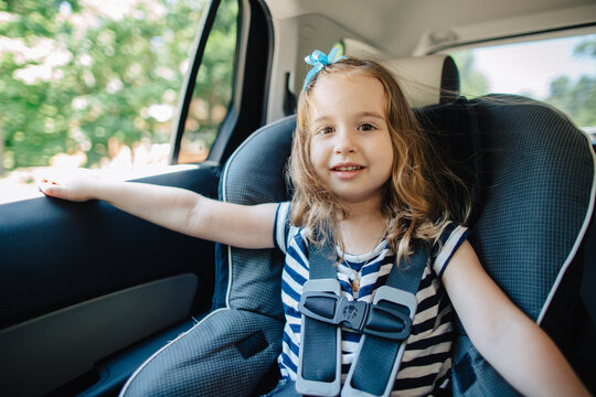 Cute young girl sitting in a car seat with the window down