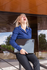 Beautiful and happy blonde in the hands of a laptop