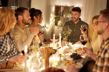 holidays, celebration and people concept - happy friends having christmas dinner party and drinking non-alcoholic red wine at home