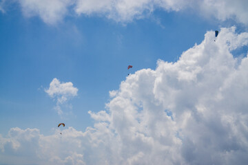 Naklejka na ściany i meble Paragliding in the cloudy blue sky.