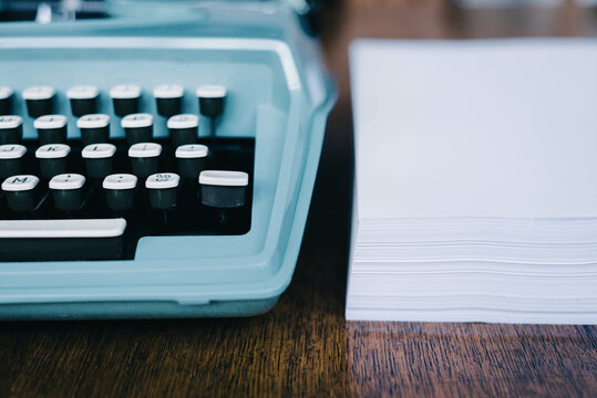 blue typewriter with a ream of blank paper