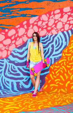 Urban skateboard girl in front of colorful graffiti mural