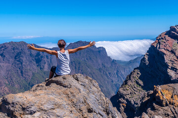 A young woman sits resting and looking at the views of the Roque de los Muchachos national park on top of the Caldera de Taburiente, La Palma, Canary Islands. Spain