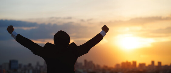 silhouette hand raised fist business man with sun lighting in morning. background city, success, grow up.