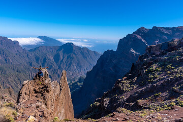A young man after finishing the trek at the top of the volcano of Caldera de Taburiente near Roque de los Muchachos looking at the incredible landscape, La Palma, Canary Islands. Spain