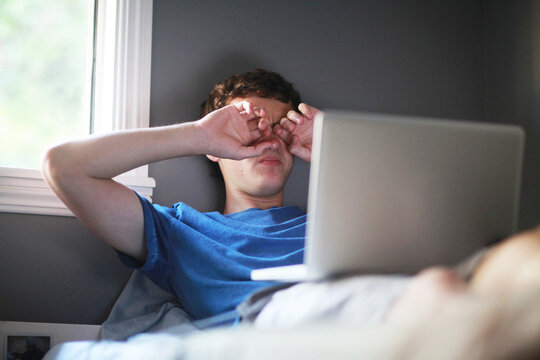 Teenager Rubbing His Eyes While Using Computer