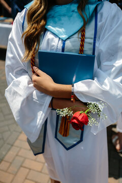 Young graduate holding diploma and rose after receiving degree from school