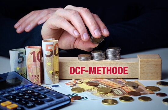 DCF-Methode. Hand baut Geldstapel auf einem Baustein mit Text. Turm aus Euro M&uuml;nzen. Taschenrechner daneben.