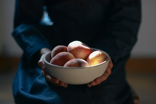 Girl holding a bowl of peaches in the light