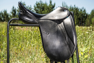 Black leather horse saddle on a supporting platform.