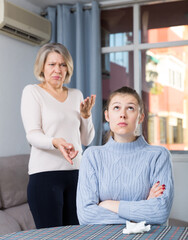 Mature mother and adult daughter quarrelling in domestic interior. High quality photo