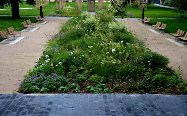 park benches lined with wood along the entire wide threshing gravel beige path, lawns, flower lush,...