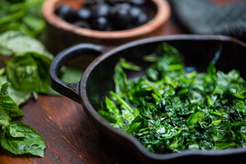 Sartén espinacas hojas verdes aceitunas negras albahaca pimiento mesa de madera para pizza lasaña...