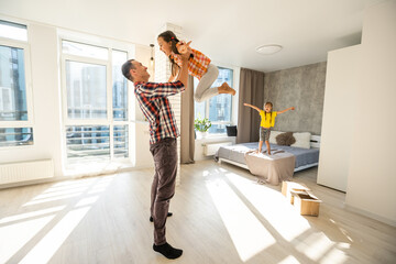 happy father and two children playing and cuddling at home on floor