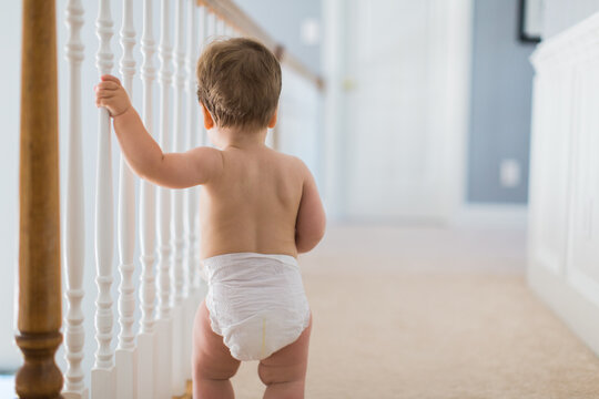 Boy toddler walking in a hallway wearing a diaper