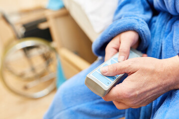 Hands of a senior citizen hold remote control