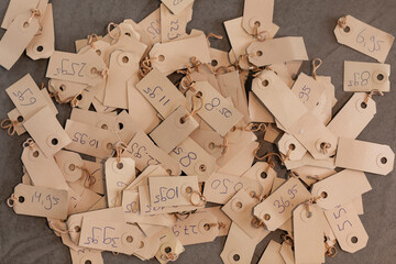 A pile of pricetags with prices on a vintage beige colored paper. Different tags with various numbers and prices laying on a grey background