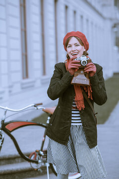 Young woman with retro camera and city bike in the street	