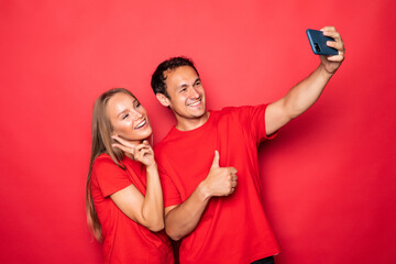 Young couple take selfie on phone isolated on red background