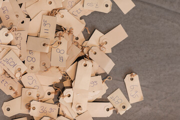 Pile of pricetags with prices on a vintage beige colored paper. Different tags with various numbers and prices laying on a grey background. Empty space on the right