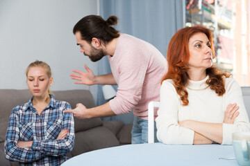 Young spouses and mother-in-low arguing indoors. High quality photo