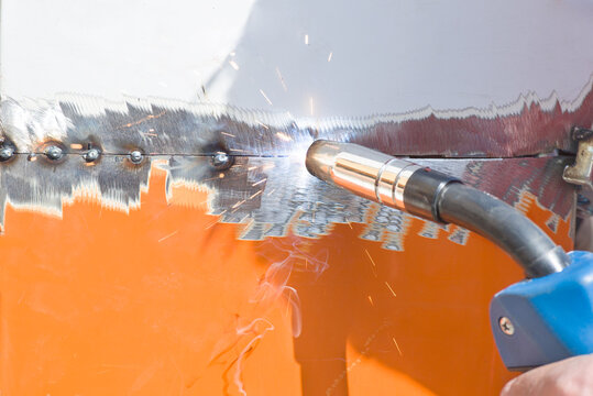 Horizontal closeup of welding gun in use