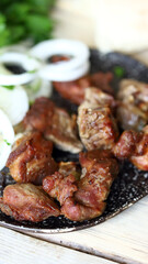 Selective focus. Fried kebab with raw onions on a plate. Greens and pita bread. Delicious pieces of meat with onion rings.