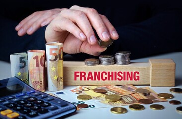 Franchising. Hand baut Geldstapel auf einem Baustein mit Text. Turm aus Euro Münzen....