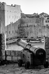 Fototapeta na wymiar Ancient cannon, selective focus, black and white. City fortress, sunny day. Scenery winter view of Mediterranean old city of Dubrovnik, famous European travel and historic destination, Croatia