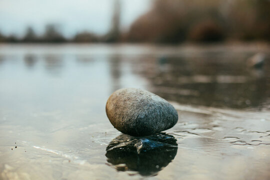 Rock sitting on top of frozen lake
