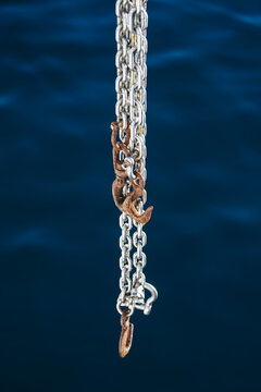 Large chain with rusty hooks hanging from a boat