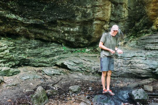 Man standing under a waterfall laughing and smiling