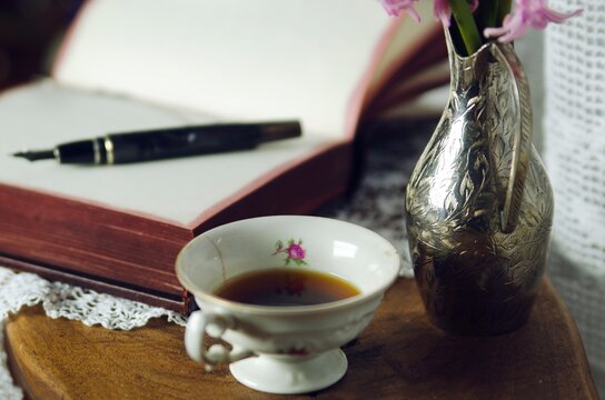 Cup of coffee and open notebook with pen on wooden desk