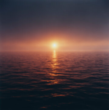Setting sun over calm ocean